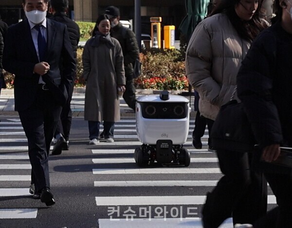 지난 7일부터 배달의민족이 서울 삼성동 테헤란로에서 실외 로봇 배달 서비스를 시작했다./ 사진: 행인들 사이로 건널목을 건너고 있는 배달 로봇/ 사진: 전휴성 기자