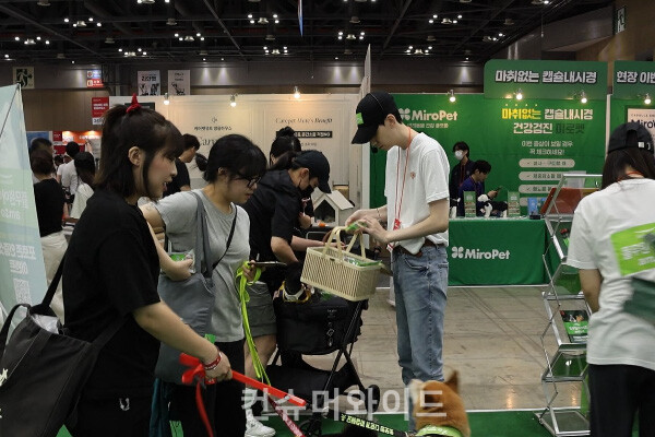 The visitors are receiving sample products at the exhibition hall of Pulmuone Amio during the 2024 Megazoo, a pet industry exhibition. ⓒConsumerwide  Husoung Jun