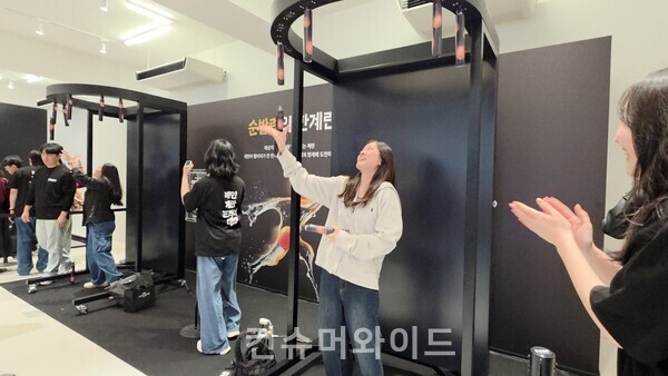 9일 배민의 팝업스토어 배민 계란프라이데이에 마련된 순발격의 한계 게임에 중국계로 추정되는 외국인이 참여해 무작위로 떨어지는 계란 봉을 잡으려고 애쓰고 있다. ⓒ컨슈머와이드 전휴성 기자