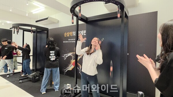 9일 배민의 팝업스토어 배민 계란프라이데이에 마련된 순발격의 한계 게임에 중국계로 추정되는 외국인이 참여해 무작위로 떨어지는 계란 봉을 잡으려고 애쓰고 있다. ⓒ컨슈머와이드 전휴성 기자