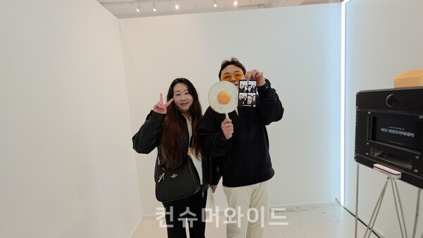  배민 계란 프라이데이 팝업에서 인생네컷을 찍고 있고 기자를 향해 포즈를 취하고 있늕 방문객들 ⓒ컨슈머와이드 전휴성 기자